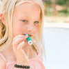 A young girl puts on Pina Colada SPF lip balm.