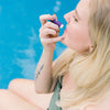 A young woman puts on Pina Colada SPF lip balm.
